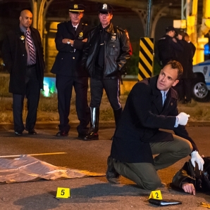 Sherlock Holmes examining corpse body at a crime scene in Elementary Season 3 Episode 8 End of Watch